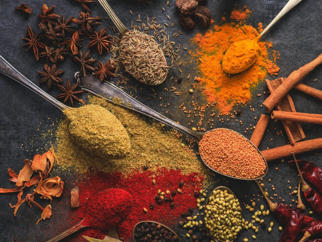 Vibrant array of spices including turmeric, cumin, and chili arranged on a dark surface.
